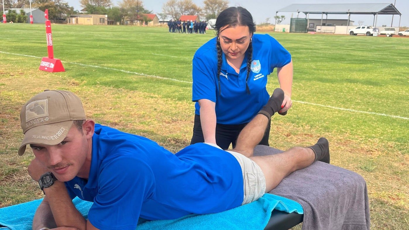 Yvonne treating a rugby player on a massage table pitch-side